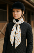 Woman wearing a black equestrian helmet and quilted jacket with a patterned scarf in an indoor arena.