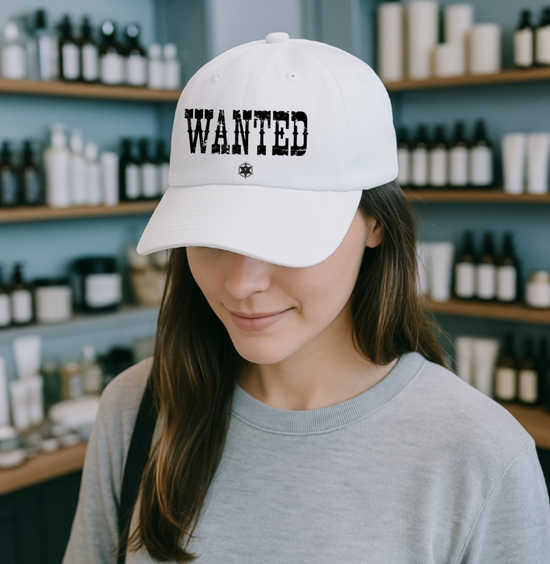 A woman shopping in a stylish boutique wearing a white Wanted Western cap with distressed lettering from Trésor Valeur’s Urban Cowgirl Collection.