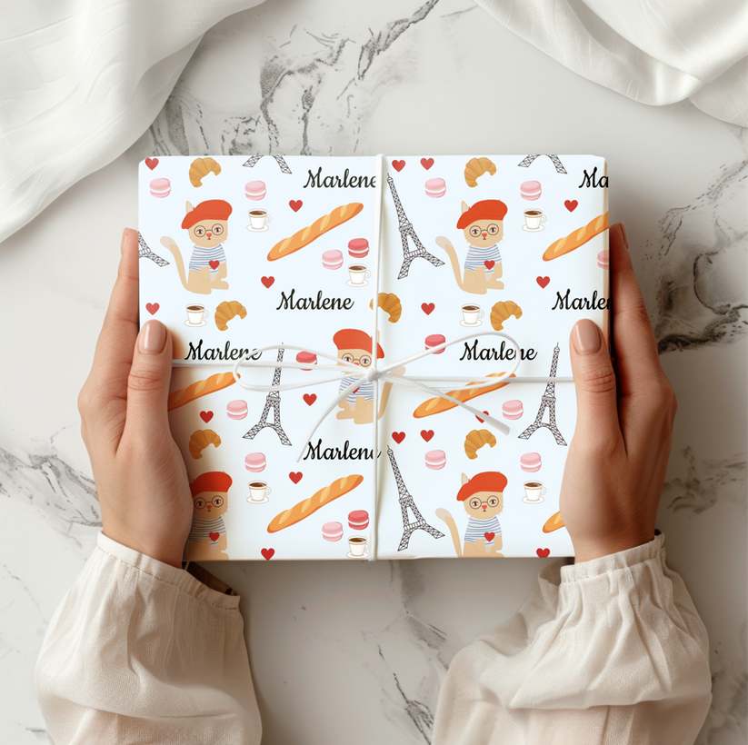 Box wrapped in Chic Parisian Cat wrapping paper.  Light blue background with a cat in a beret, macarons, coffee, croissants and the Eiffel Tower.