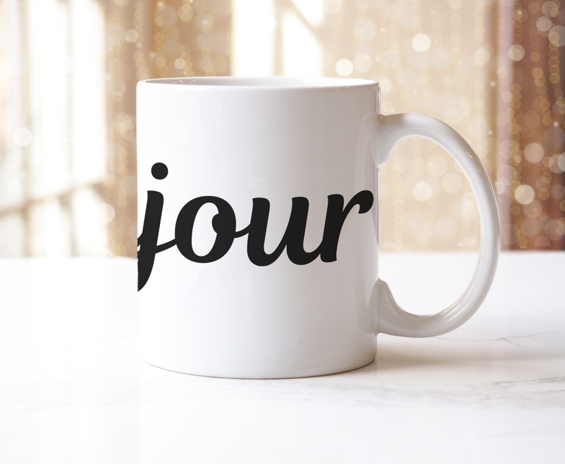 White mug with 'bonjour' printed on it against a blurred background
