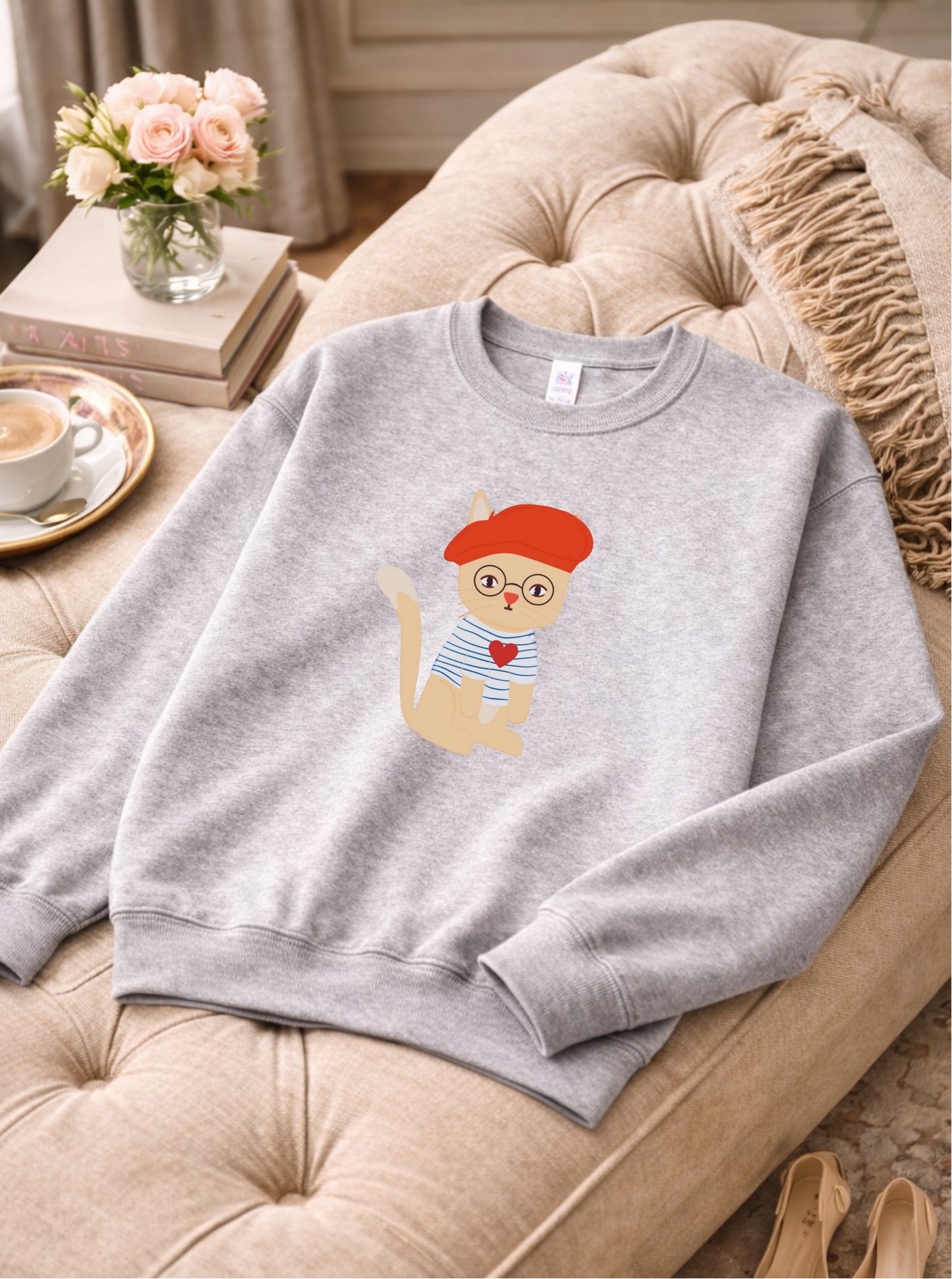 Gray sweatshirt with a cat graphic on a beige couch
