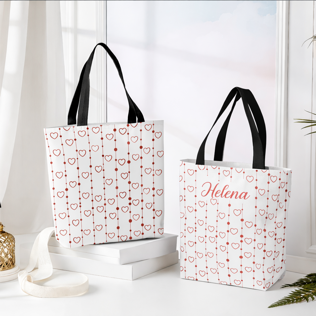 Two tote bags with heart patterns and a name on a white surface.