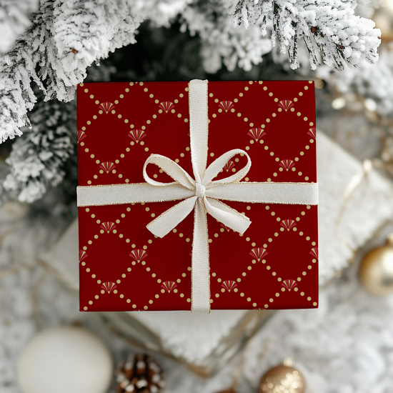 Red and gold elegant art deco patterned wrapping paper on gift box with white ribbon under a decorated Christmas tree