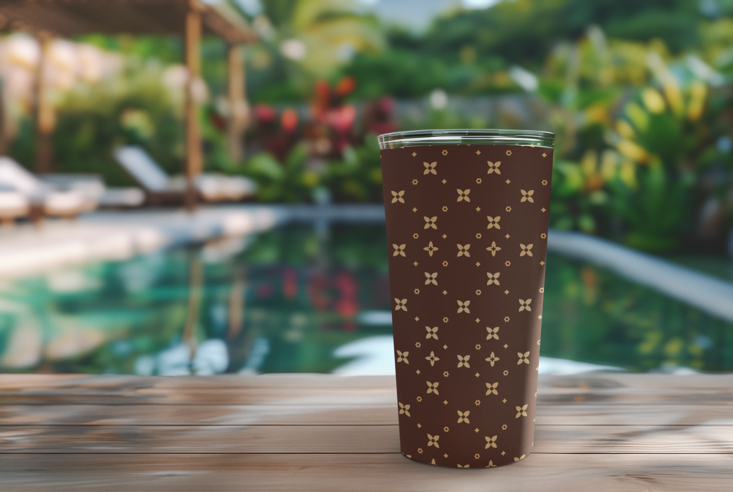 Brown tumbler with a pattern on a wooden table with a pool and greenery in the background